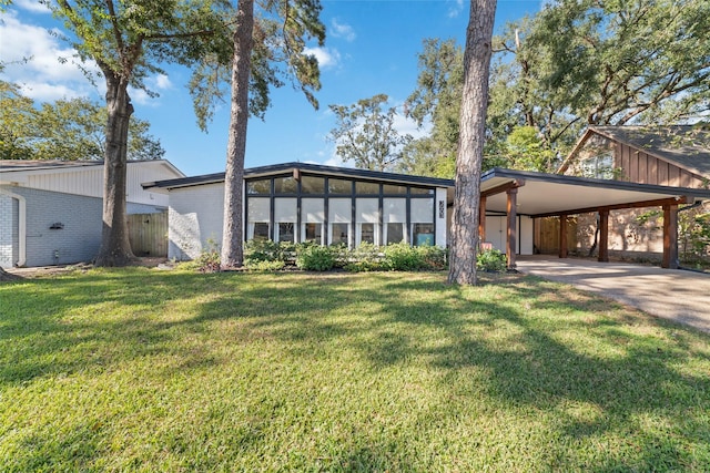 mid-century inspired home with brick siding, driveway, an attached carport, and a front lawn