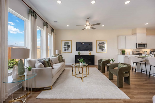 living room with a ceiling fan, recessed lighting, visible vents, and wood finished floors