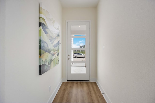 doorway with baseboards and wood finished floors