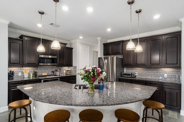 kitchen featuring a breakfast bar, a spacious island, visible vents, appliances with stainless steel finishes, and dark brown cabinetry