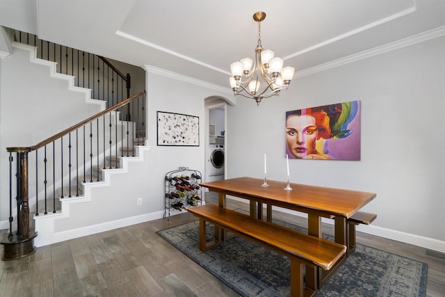 dining space with wood finished floors, a raised ceiling, washer / dryer, and baseboards