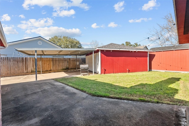 view of yard with an outbuilding, a carport, a patio area, and fence