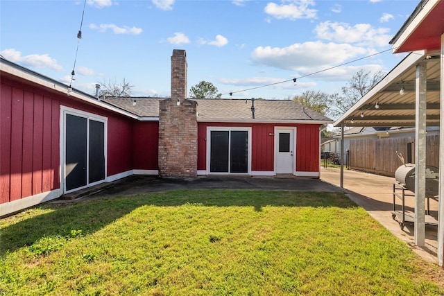 back of house with a shingled roof, a patio area, a yard, and fence