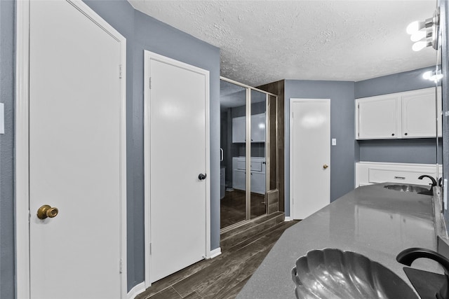 interior space with a sink, a textured ceiling, and wood finished floors