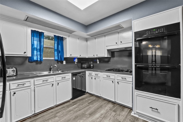 kitchen with white cabinets, a sink, under cabinet range hood, and black appliances