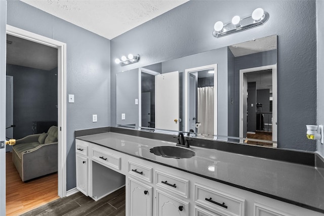 ensuite bathroom with ensuite bathroom, a textured wall, wood finished floors, and vanity