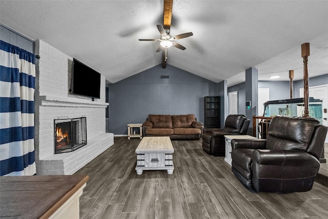 living room featuring dark wood finished floors, a fireplace, lofted ceiling with beams, ceiling fan, and a textured ceiling