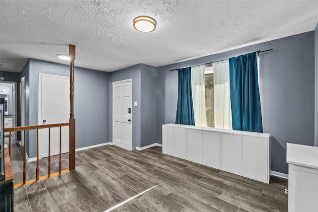 foyer featuring a textured ceiling, baseboards, and wood finished floors