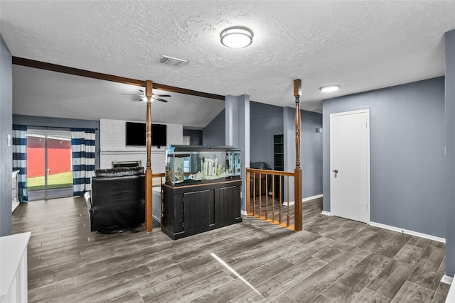 kitchen with visible vents, a ceiling fan, vaulted ceiling, a textured ceiling, and wood finished floors