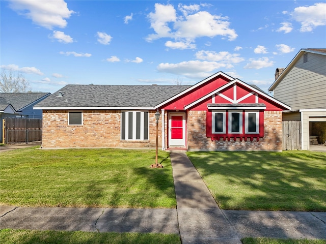 view of front of home with a front yard, brick siding, and roof with shingles