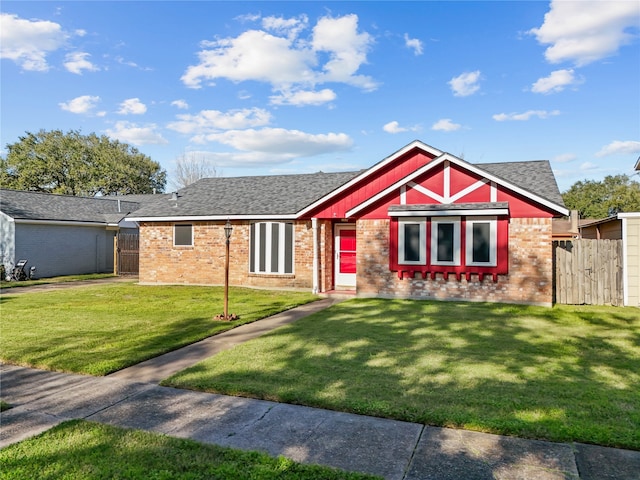 view of front of property with brick siding, a front yard, fence, and a shingled roof