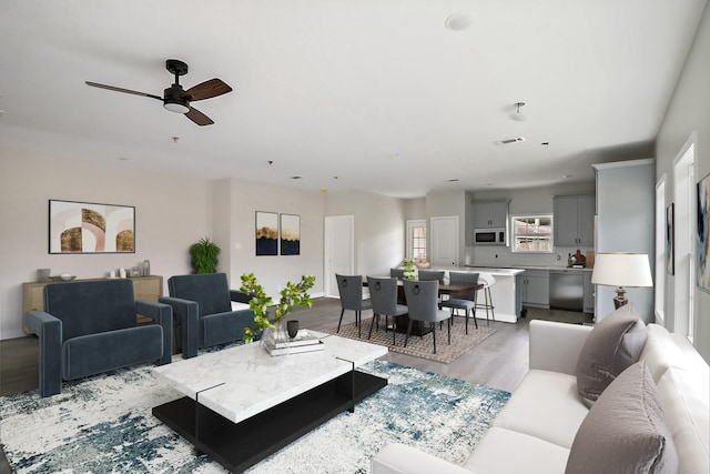 living room featuring ceiling fan, wood finished floors, and visible vents