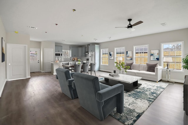 living area featuring ceiling fan, dark wood-type flooring, visible vents, and baseboards