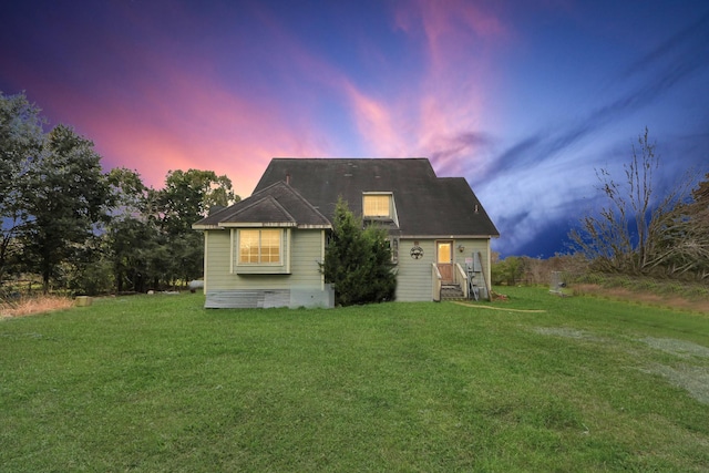 back of house at dusk with a lawn