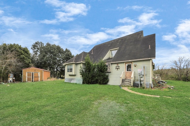 rear view of property featuring a storage shed, a yard, and an outbuilding