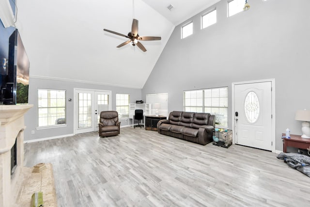 living room with french doors, a fireplace, baseboards, and wood finished floors