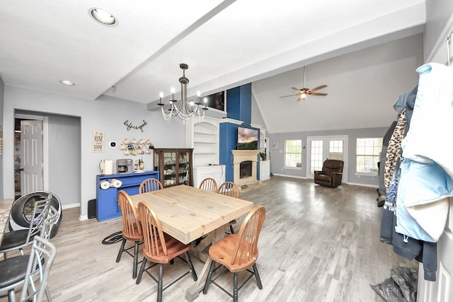 dining space featuring vaulted ceiling, light wood finished floors, a fireplace, and baseboards