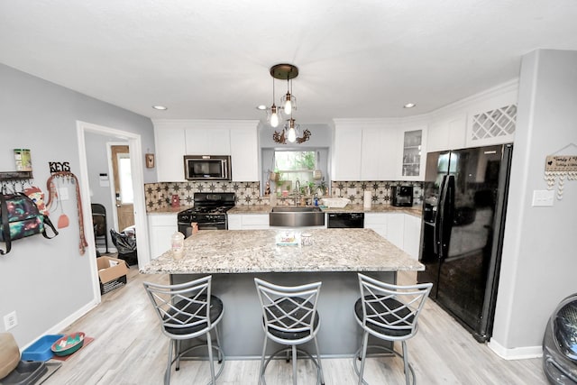 kitchen featuring black appliances, tasteful backsplash, a kitchen island, and white cabinets