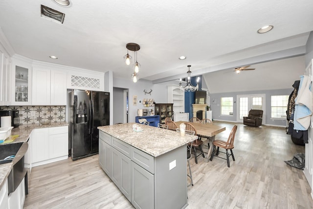 kitchen featuring light wood-style floors, visible vents, black fridge, and a center island