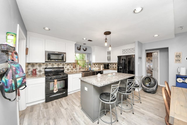 kitchen featuring black appliances, light wood-style flooring, and white cabinets