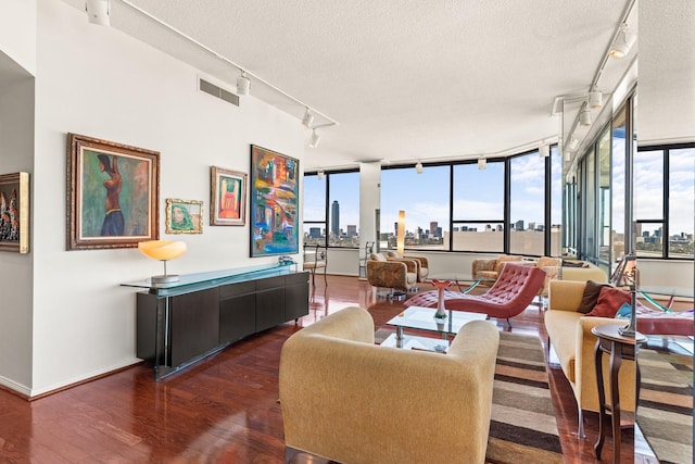 living room featuring visible vents, dark wood finished floors, rail lighting, a view of city, and a textured ceiling