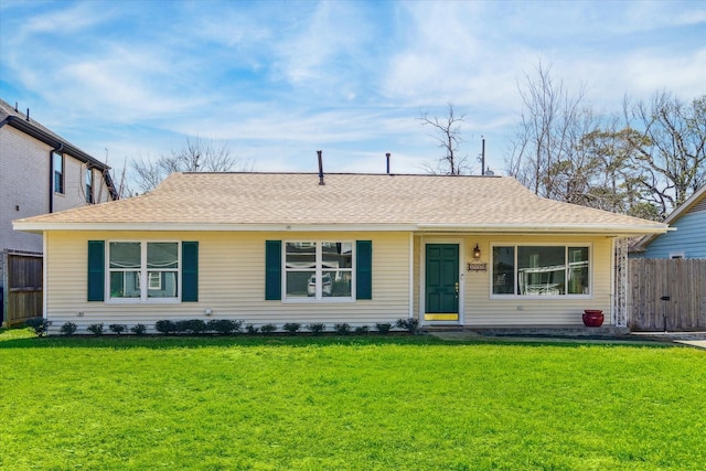 ranch-style home with a front lawn, a shingled roof, and fence