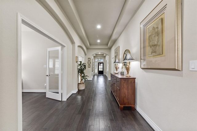 hallway with arched walkways, recessed lighting, dark wood-type flooring, and baseboards