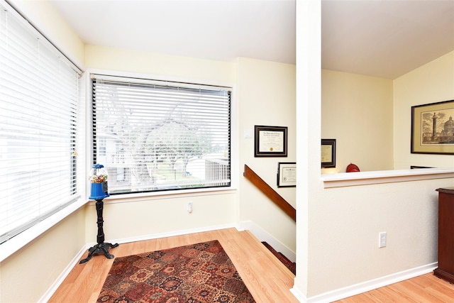 interior space featuring baseboards, an upstairs landing, and wood finished floors