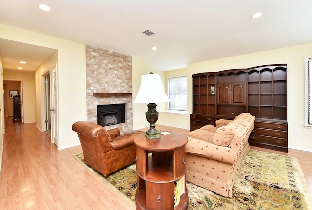 living room featuring a large fireplace, baseboards, visible vents, light wood-type flooring, and recessed lighting