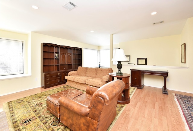 living room featuring a wealth of natural light, light wood-type flooring, and visible vents