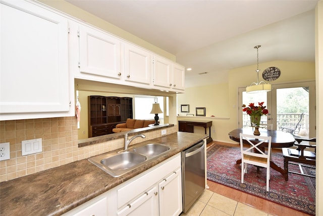 kitchen with decorative backsplash, white cabinets, dark countertops, stainless steel dishwasher, and a sink