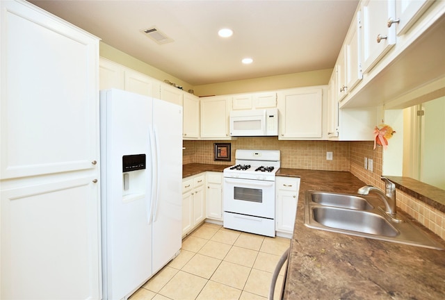 kitchen featuring white appliances, tasteful backsplash, visible vents, dark countertops, and a sink