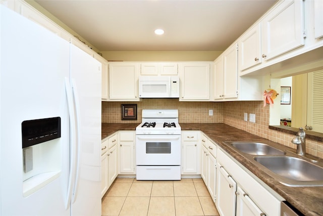 kitchen with dark countertops, white appliances, a sink, and light tile patterned floors