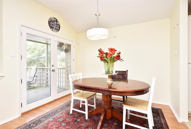 dining space with light wood-style floors, baseboards, vaulted ceiling, and french doors