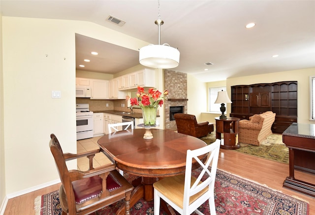 dining area with recessed lighting, a large fireplace, visible vents, and light wood-style flooring