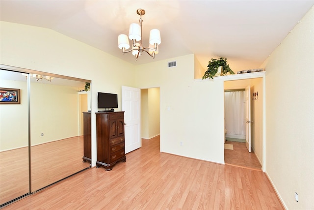 unfurnished bedroom with visible vents, light wood-style flooring, an inviting chandelier, vaulted ceiling, and a closet