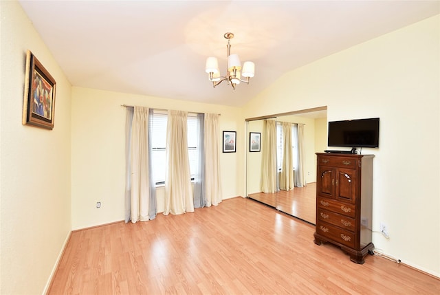 empty room featuring light wood-style floors, baseboards, vaulted ceiling, and an inviting chandelier