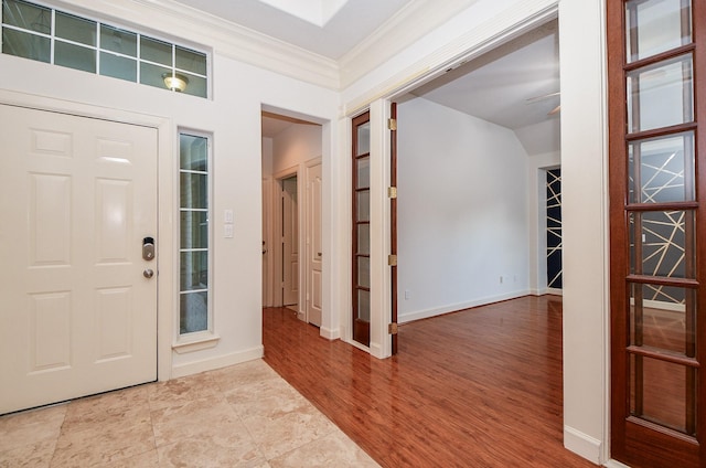 foyer entrance with ornamental molding, ceiling fan, baseboards, and wood finished floors