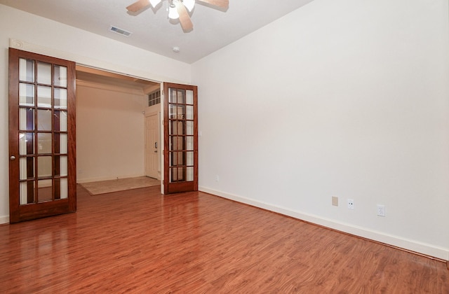 empty room with visible vents, baseboards, wood finished floors, and french doors