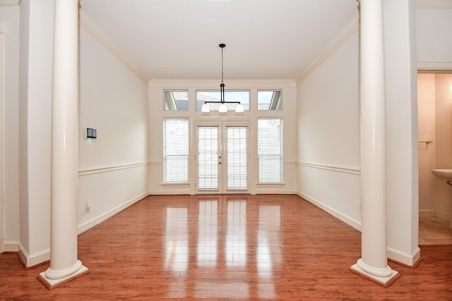 interior space with baseboards, ornamental molding, wood finished floors, and ornate columns