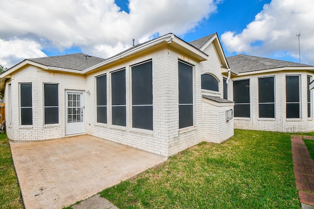 back of property with a yard, brick siding, a patio, and a shingled roof