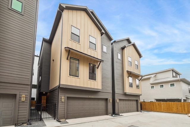 townhome / multi-family property with an attached garage, fence, and board and batten siding