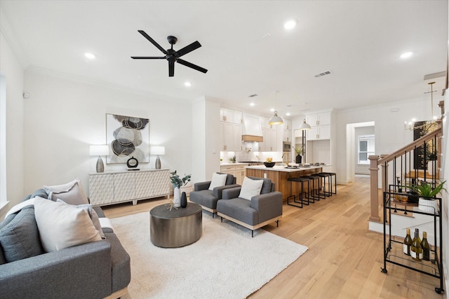 living room with light wood finished floors, visible vents, ornamental molding, stairs, and recessed lighting