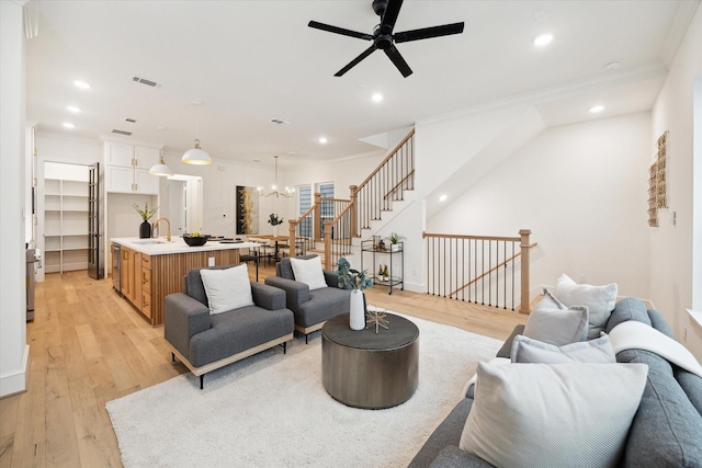 living room with ornamental molding, light wood finished floors, visible vents, and recessed lighting