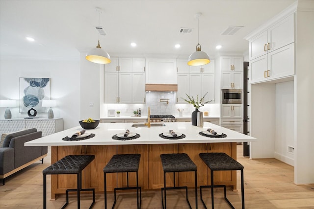 kitchen featuring visible vents, stainless steel microwave, light countertops, white cabinetry, and backsplash