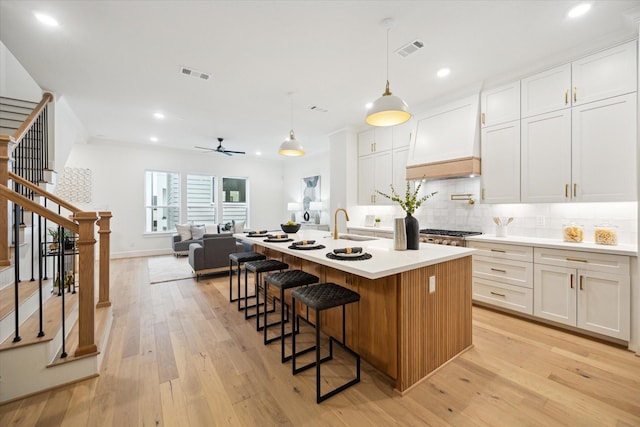 kitchen featuring visible vents, stainless steel gas cooktop, light wood-style flooring, and custom exhaust hood