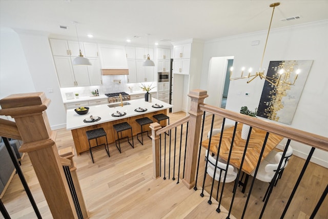 staircase featuring ornamental molding, visible vents, and wood finished floors