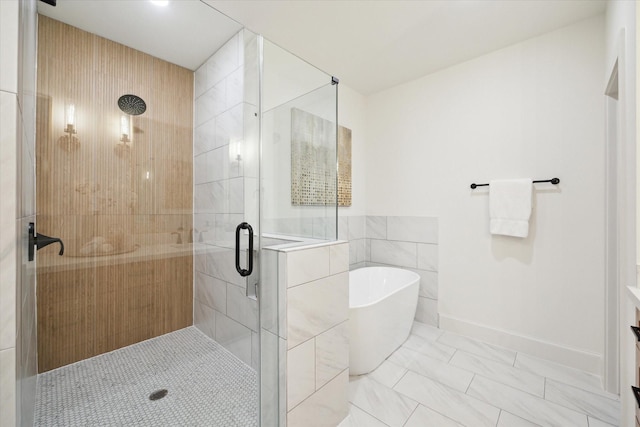 full bathroom with a stall shower, a freestanding bath, tile walls, and baseboards