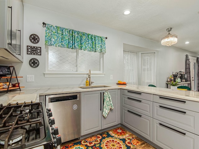 kitchen featuring stainless steel appliances, a sink, gray cabinetry, and light stone countertops