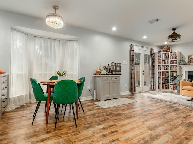 dining area featuring recessed lighting, a fireplace, wood finished floors, visible vents, and french doors